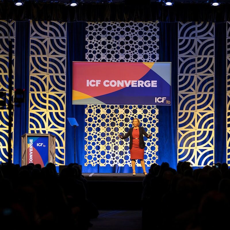 Speaker presenting on stage at the ICF Converge conference in front of a live audience.