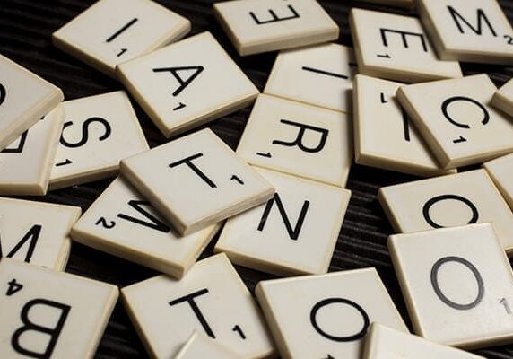 scrabble letters in pile on dark wood table