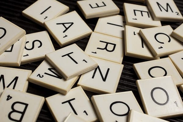 scrabble letters in pile on dark wood table