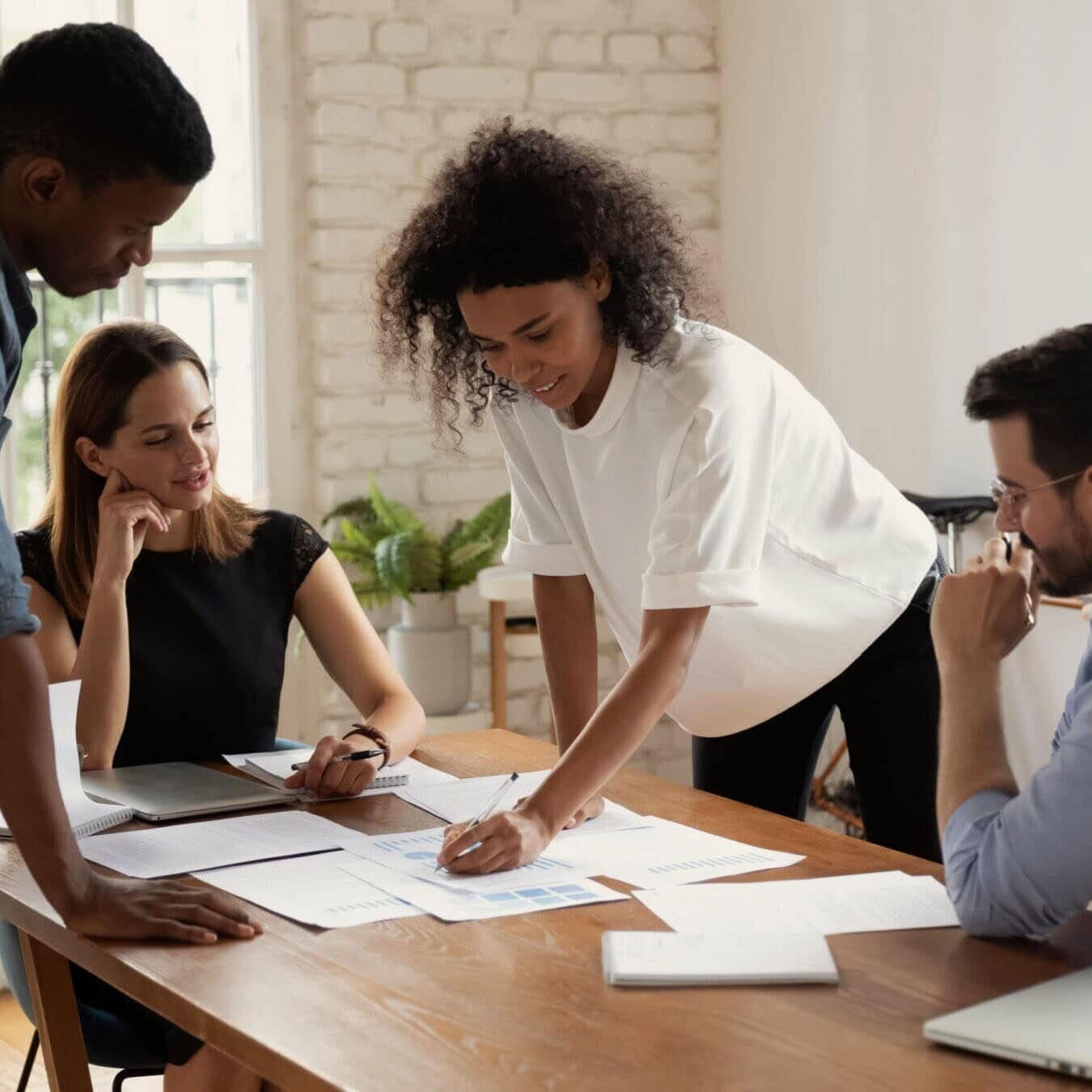 A group of professionals work together in an office reviewing several documents.