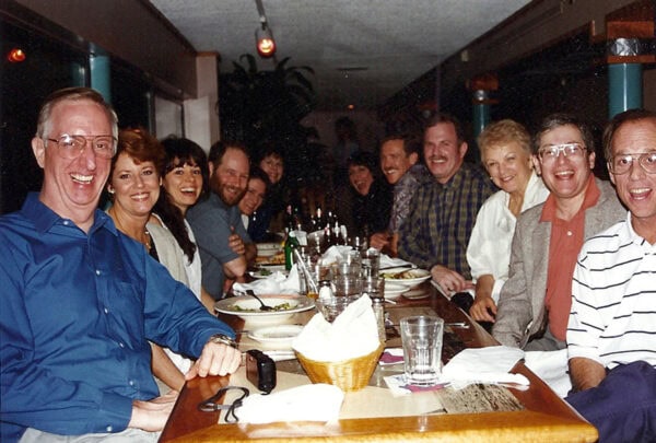 A historical photo of one of the first boards of directors for the International Coaching Federation, seated around a dining table during a meal.