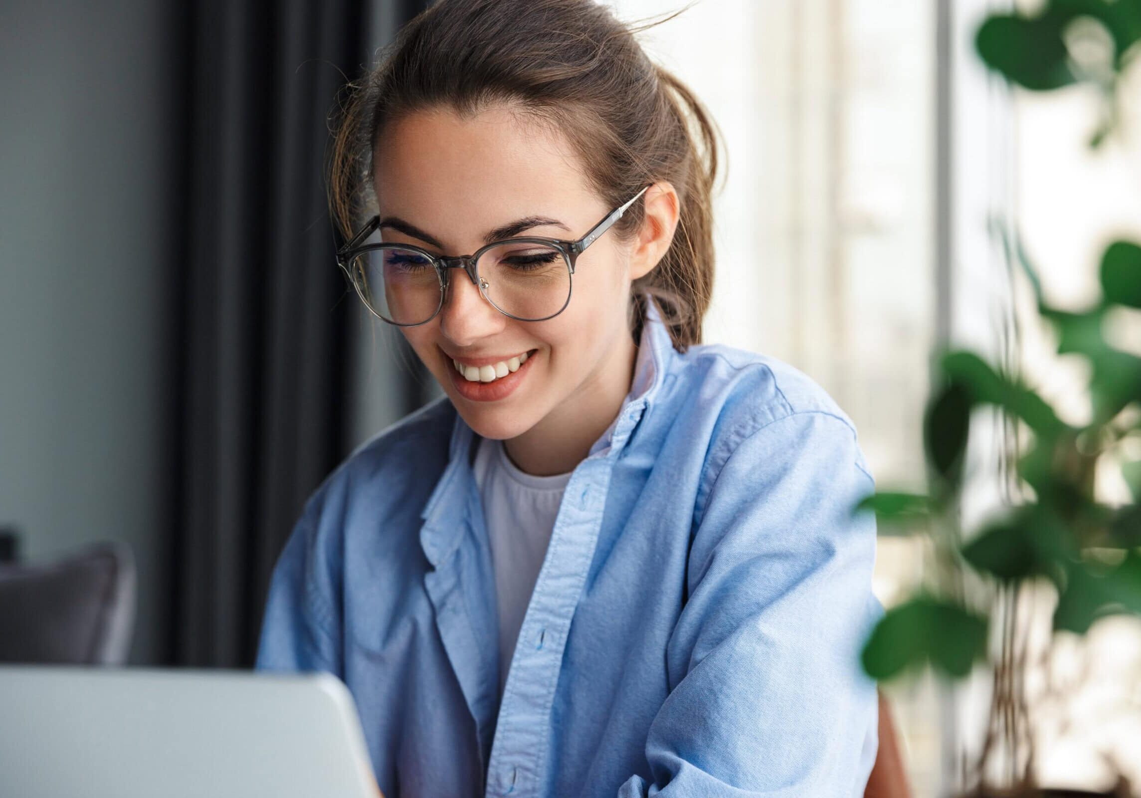 Woman smiling while working on a laptop at a desk