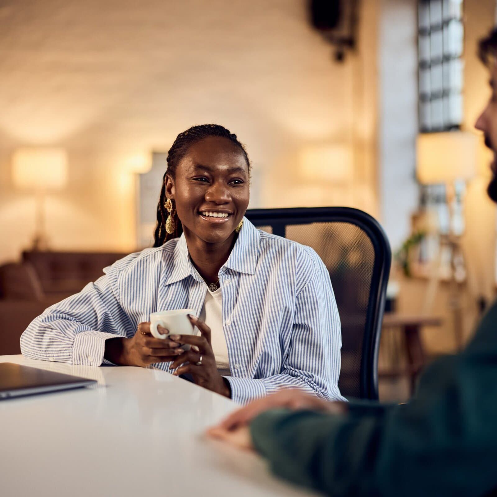 Two professionals having a conversation at a table in a modern office