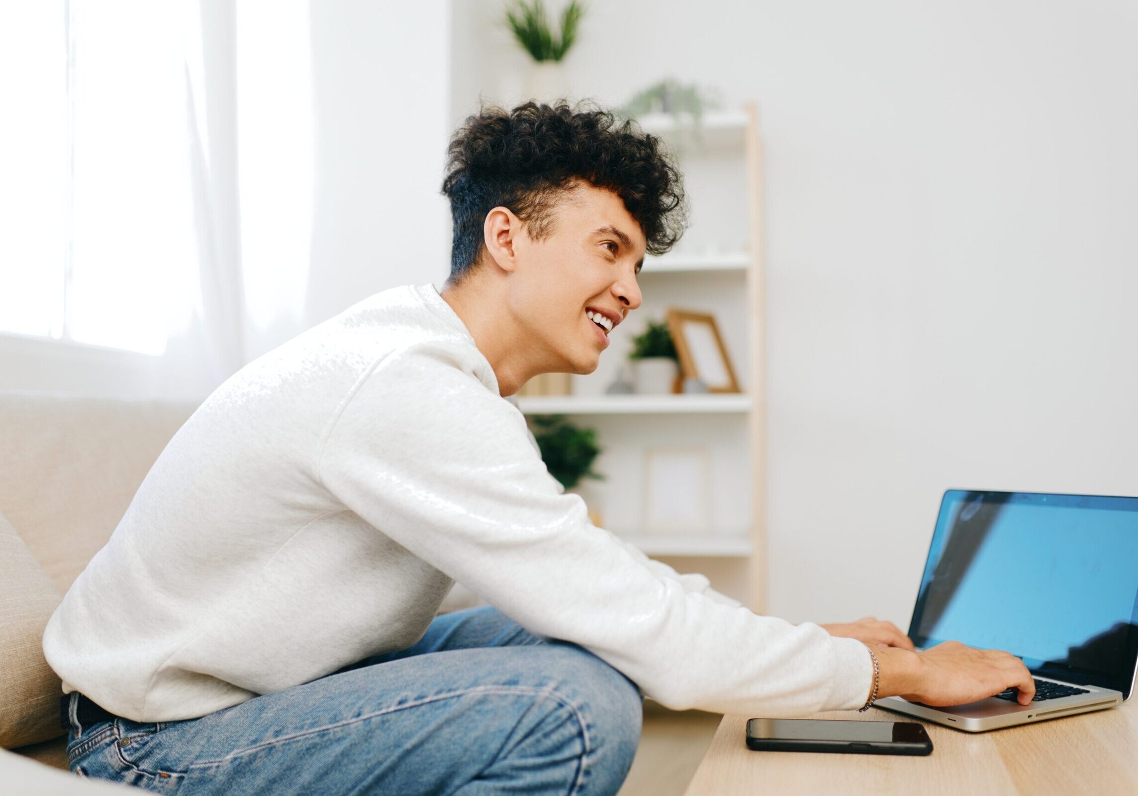 Man smiling while using a laptop in a casual home setting