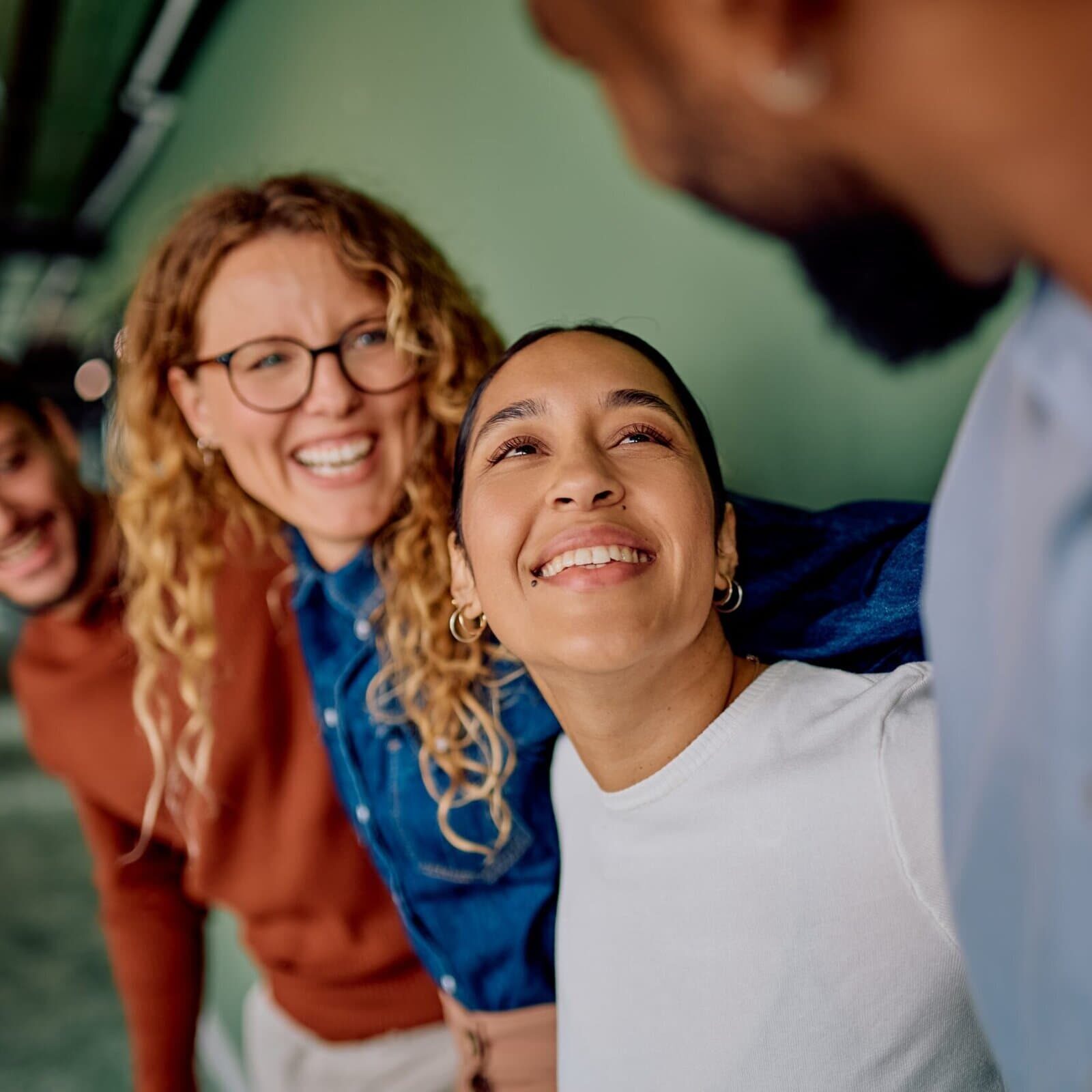 Group of coworkers smiling and laughing together in a modern office hallway