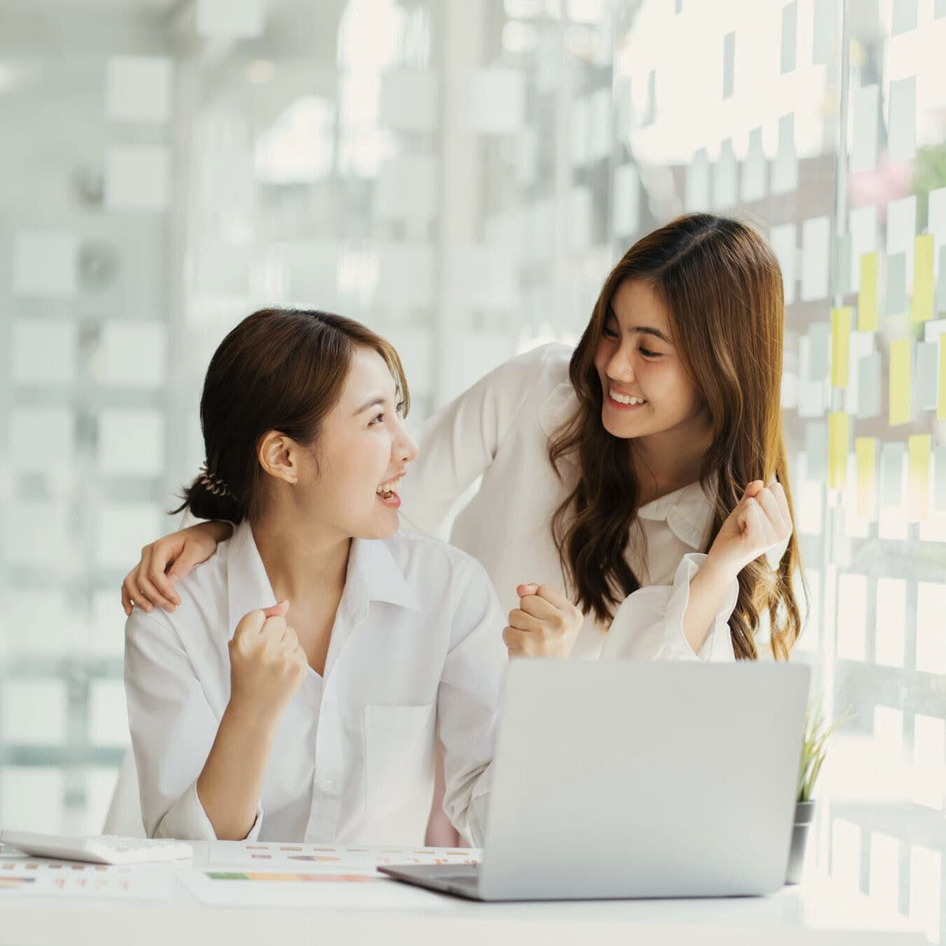 Two women look a laptop in an a calm office setting.