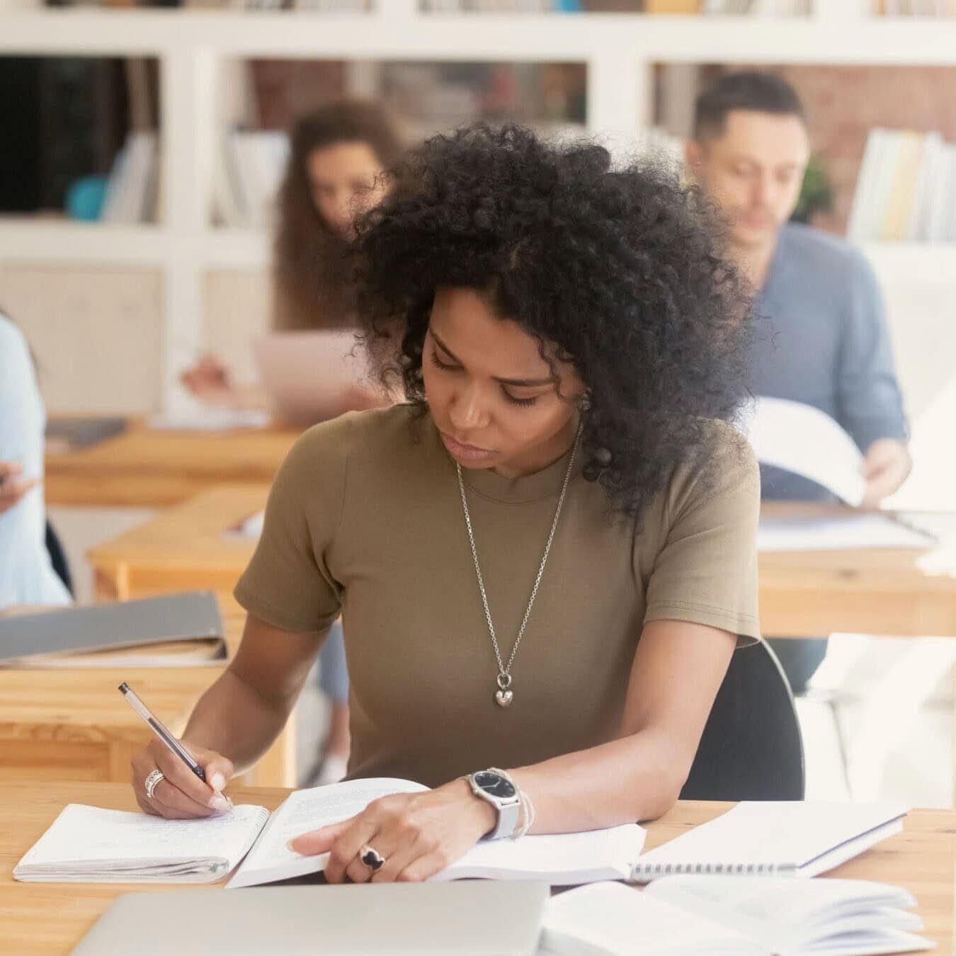 A student is writing notes in her notebook in a classroom