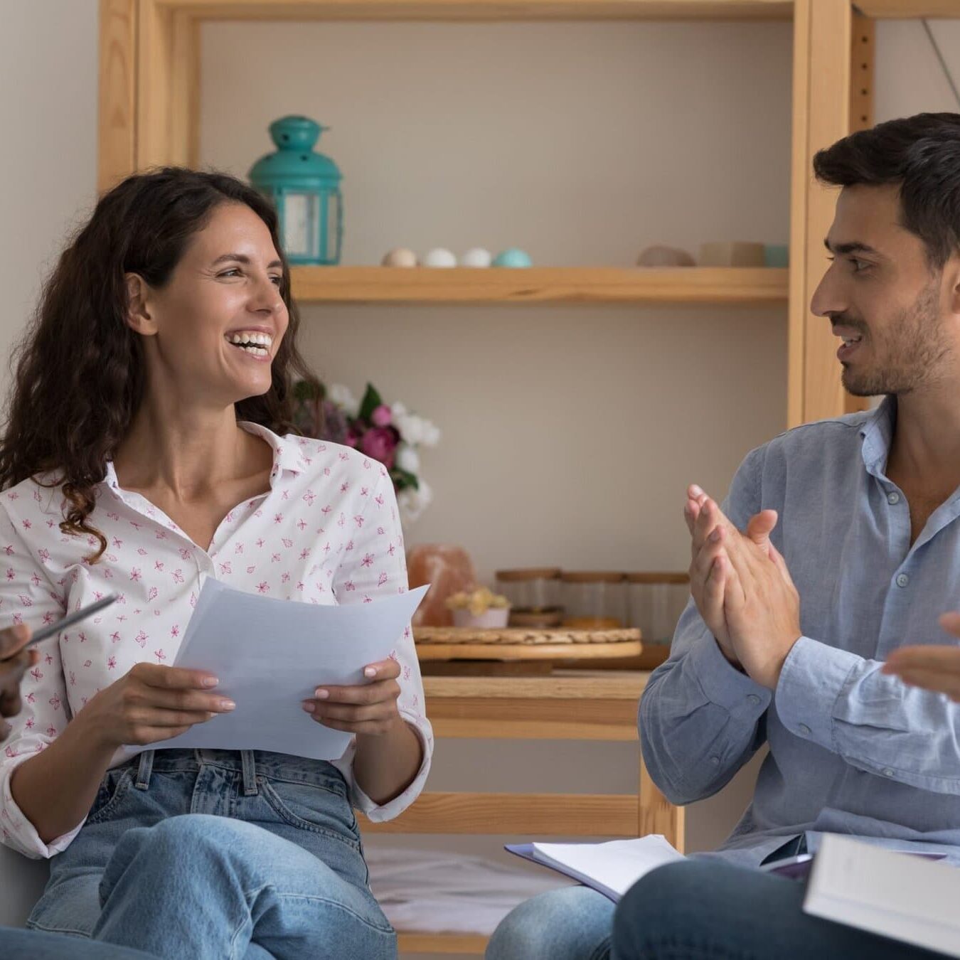 Diverse business team applauding a woman holding papers during a collaborative meeting