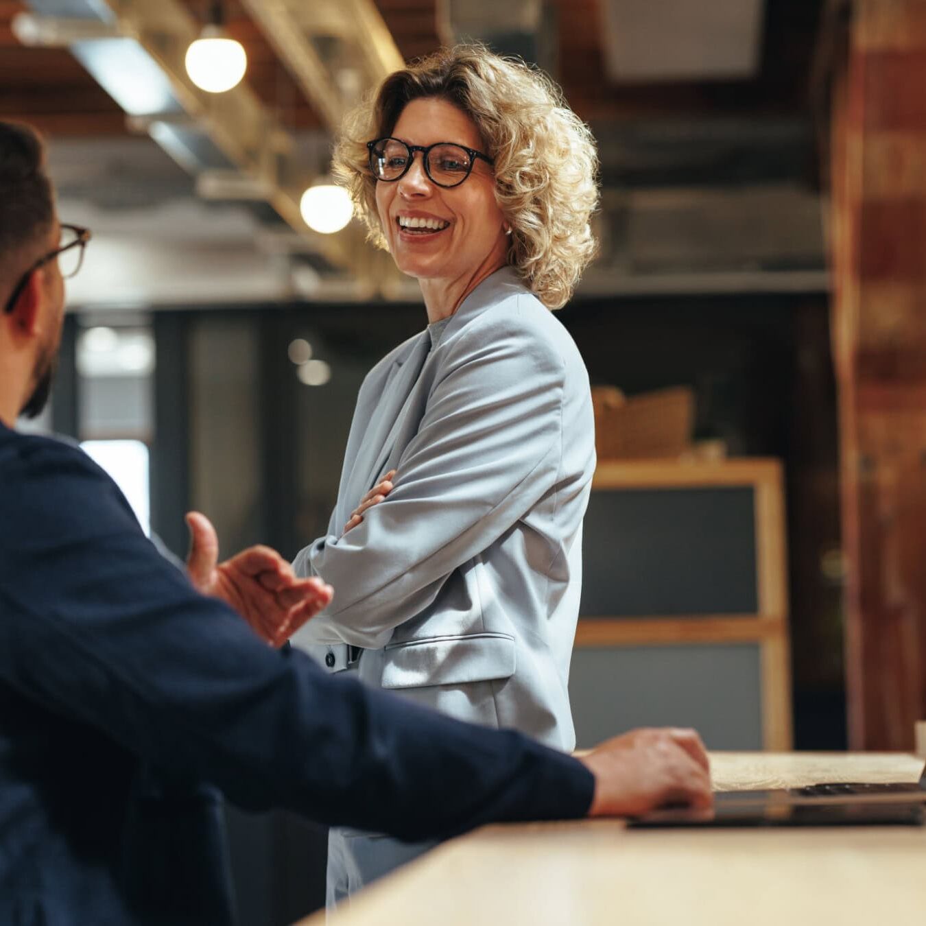 Woman talking to a man in an industry style office about the ICF Credential Requirements