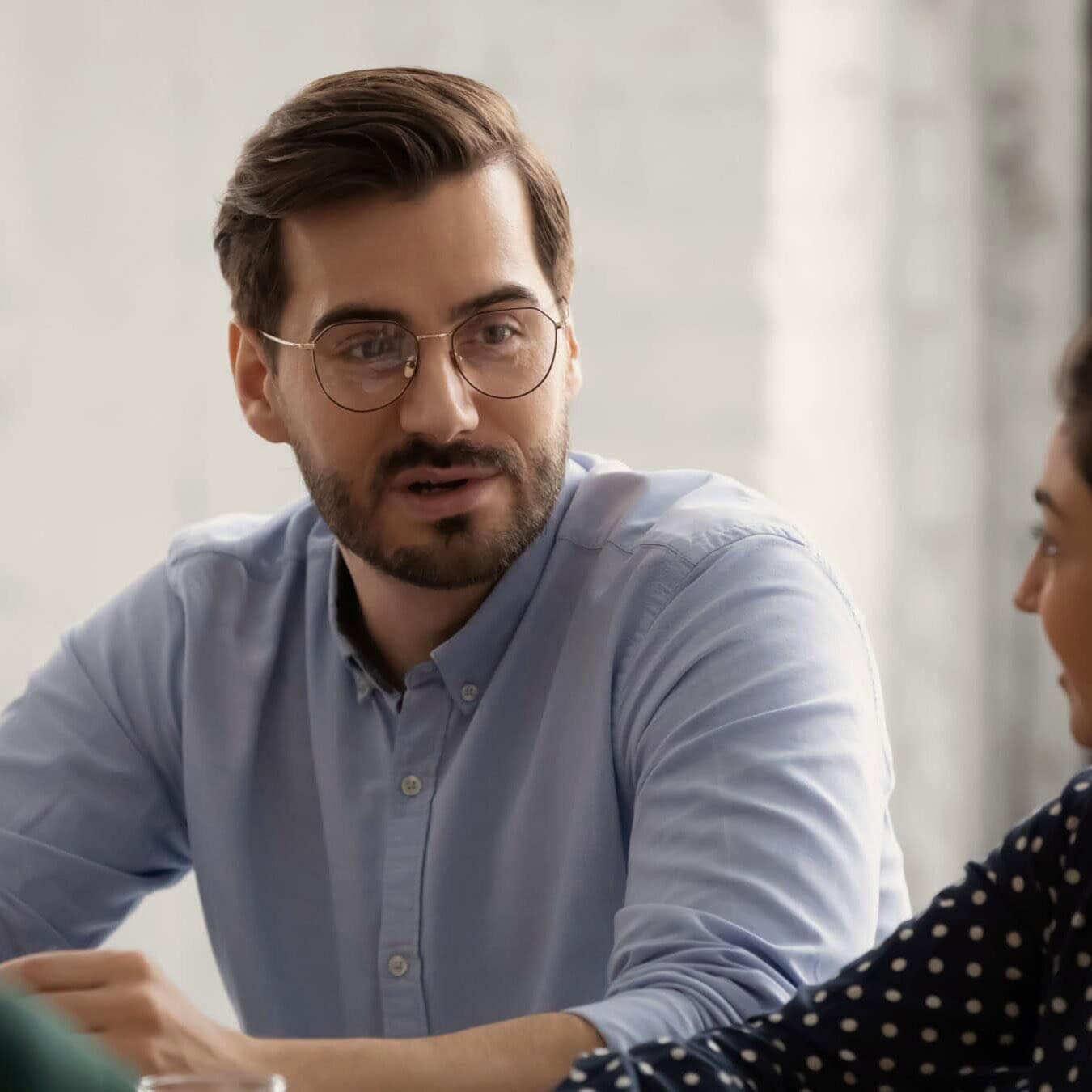 A man is talking with another woman in an office setting diving into coaching consumer complaints