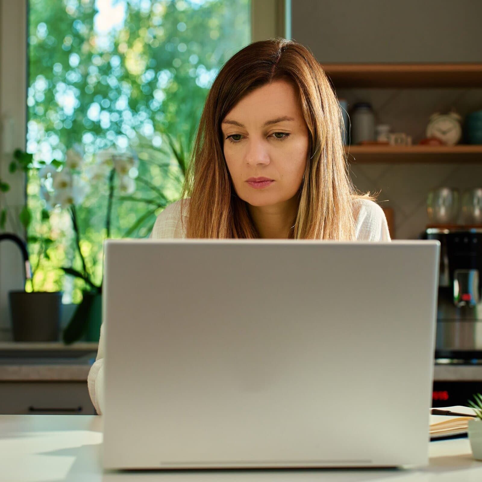 Woman working on a laptop at a desk in a home office setting