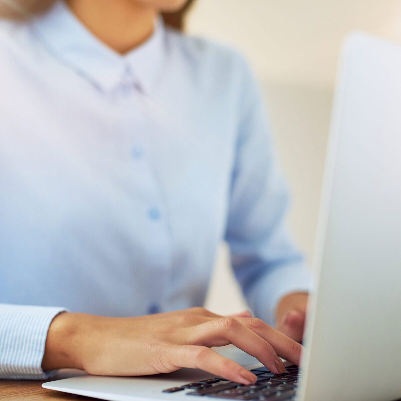 Close-up of a professional woman typing on a laptop keyboard