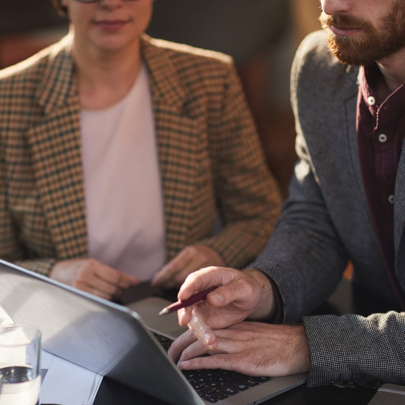 Two business professionals pointing at and reviewing information on a laptop during a meeting