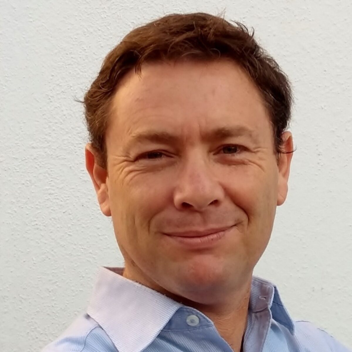 Headshot of José Manuel Estrada, PCC. Man smiling with a blue shirt in front of