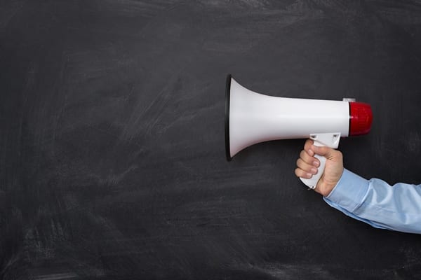 loudspeaker being held in front of a chalkboard
