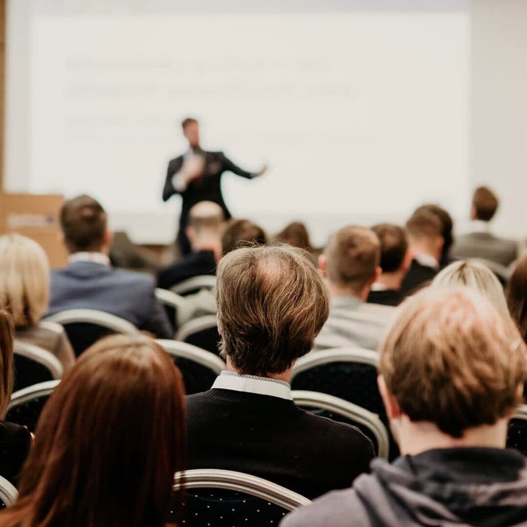 large conference hall with speaker at the front giving a presentation