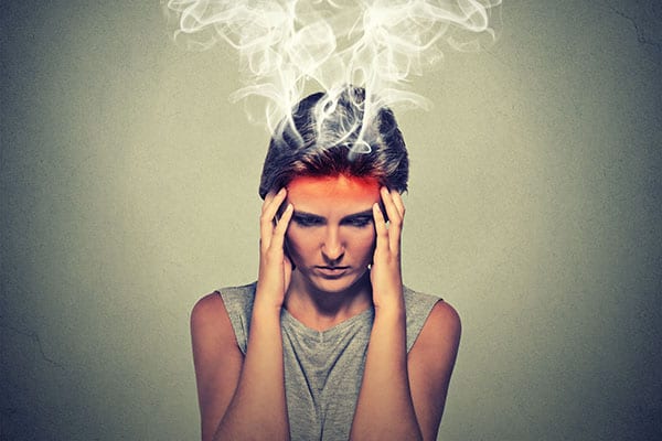 woman stressed with hands at temples and head emitting smoke