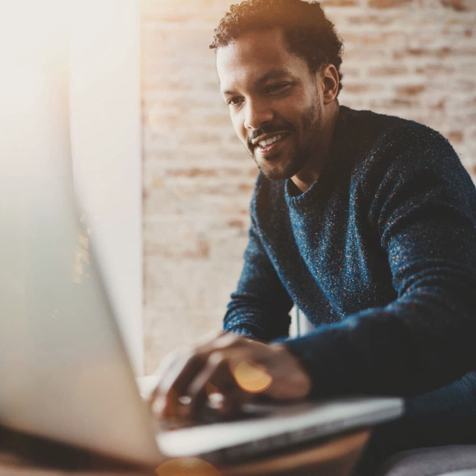 man leaning forward to put his hand on a laptop keyboard